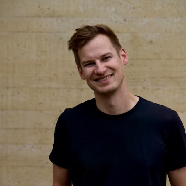 CEO im Porträt, lächelnd, vor einer Betonwand.