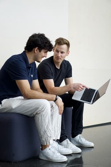 Two team members sitting together, discussing work on a laptop.